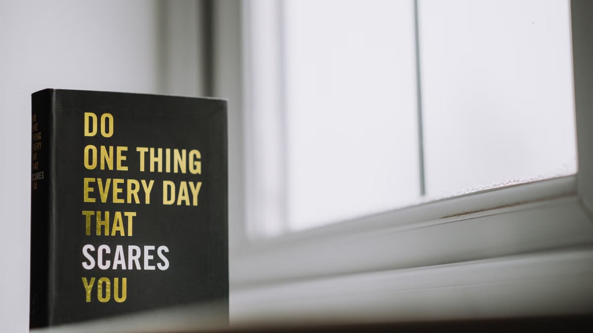 Rectangular shaped book with printed title on black hardcover on windowsill in house in daytime